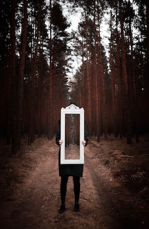 Person holding mirror in forest